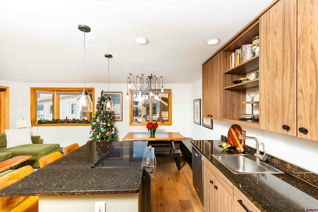 kitchen with dishwasher, dark stone counters, sink, light wood-type flooring, and decorative light fixtures