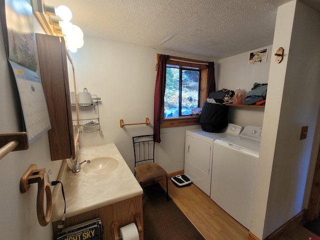 laundry room featuring hardwood / wood-style flooring, sink, a textured ceiling, and independent washer and dryer