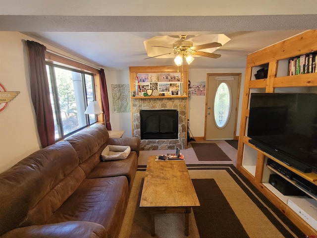 living room with carpet, a textured ceiling, a stone fireplace, and ceiling fan