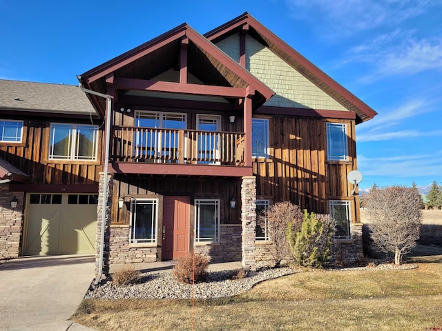 craftsman-style home with a balcony, a front lawn, and a garage