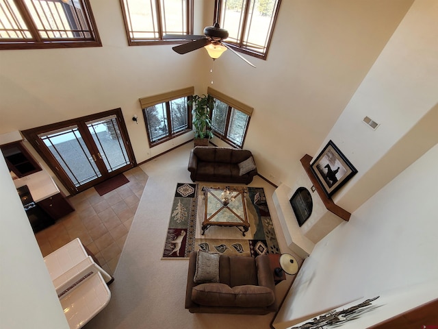 living room with a high ceiling, ceiling fan, and plenty of natural light