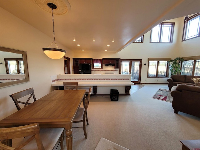 dining area with a high ceiling, a healthy amount of sunlight, and light colored carpet