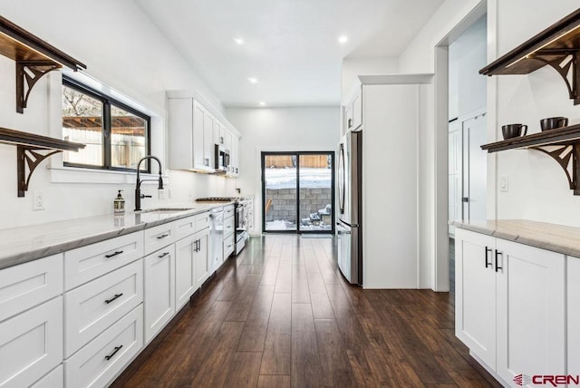 kitchen featuring appliances with stainless steel finishes, dark hardwood / wood-style flooring, light stone counters, sink, and white cabinetry