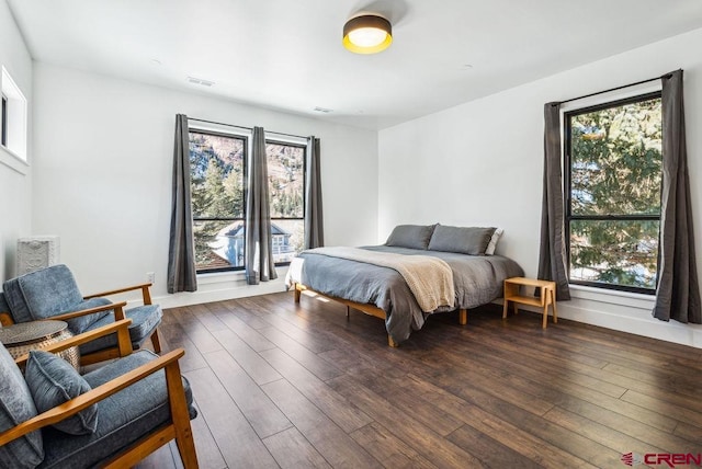 bedroom with dark hardwood / wood-style flooring and multiple windows