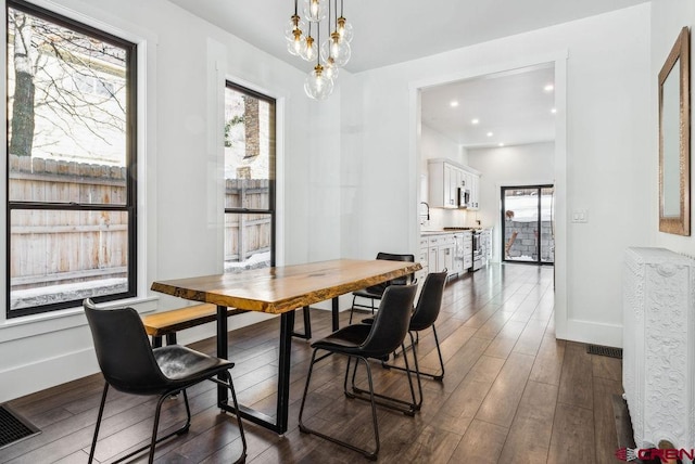 dining area with sink, a chandelier, and dark hardwood / wood-style floors