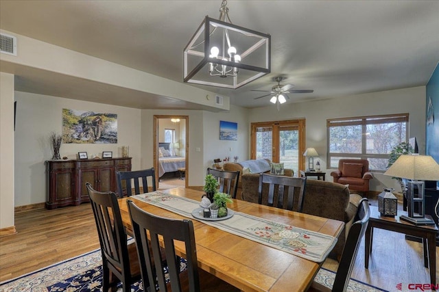 dining room with wood-type flooring and ceiling fan with notable chandelier