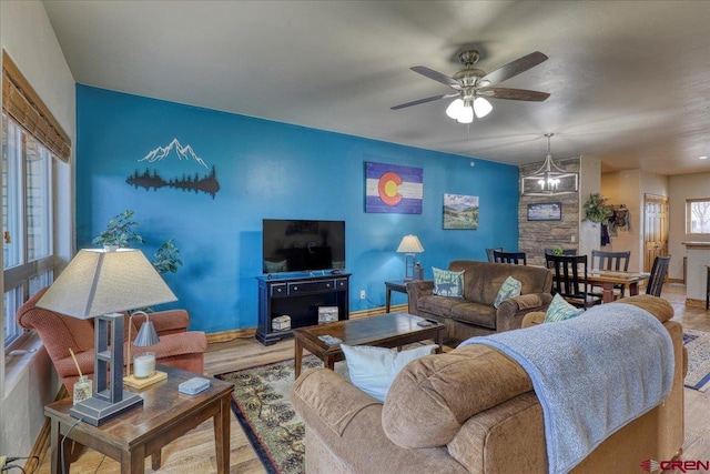 living room featuring light hardwood / wood-style floors and ceiling fan with notable chandelier