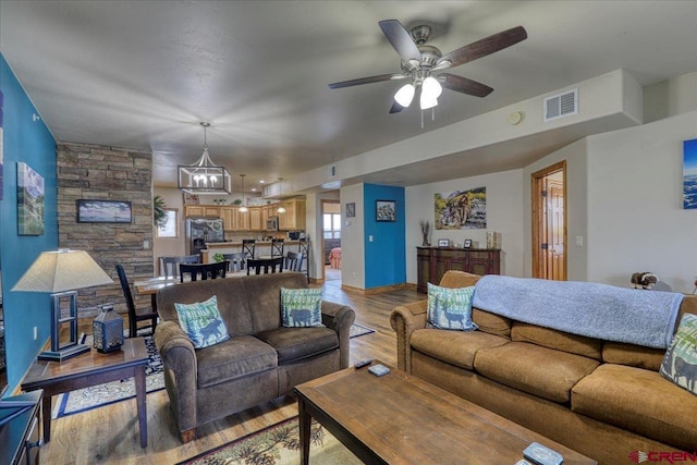 living room with ceiling fan with notable chandelier and light wood-type flooring