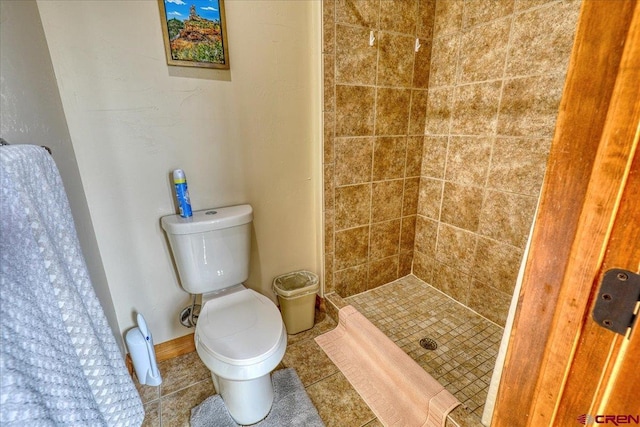 bathroom featuring tile patterned floors, toilet, and a tile shower