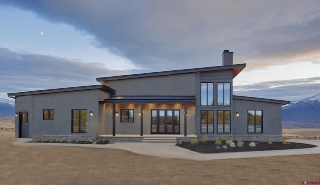 back house at dusk with a mountain view and french doors