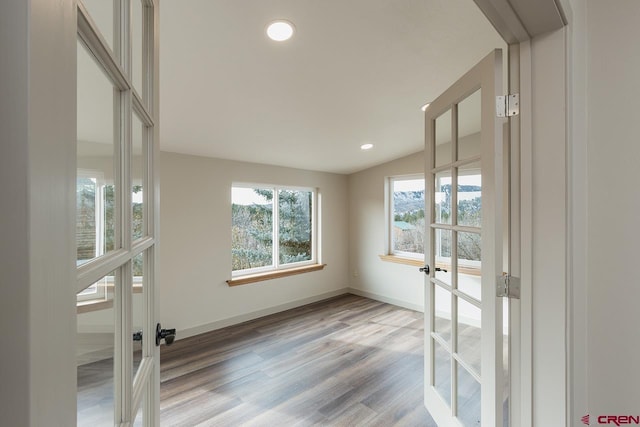 empty room featuring french doors, vaulted ceiling, and light wood-type flooring