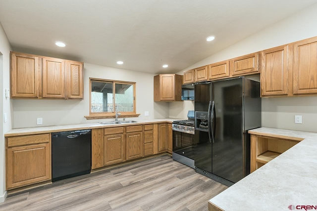 kitchen with sink, light hardwood / wood-style floors, vaulted ceiling, and black appliances