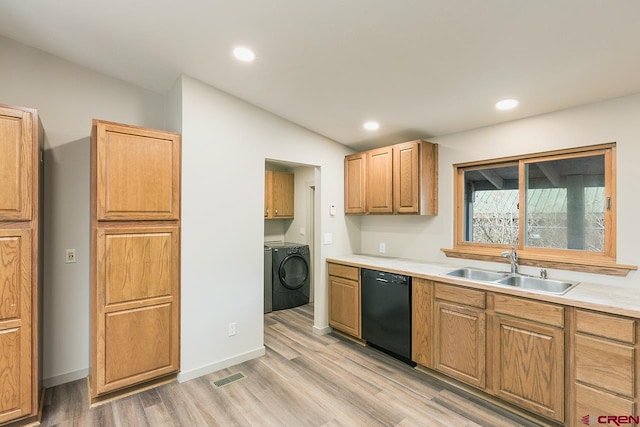 kitchen with sink, vaulted ceiling, black dishwasher, light hardwood / wood-style floors, and washing machine and clothes dryer