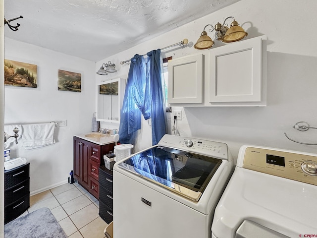 laundry area featuring cabinets, washing machine and dryer, light tile patterned floors, and sink