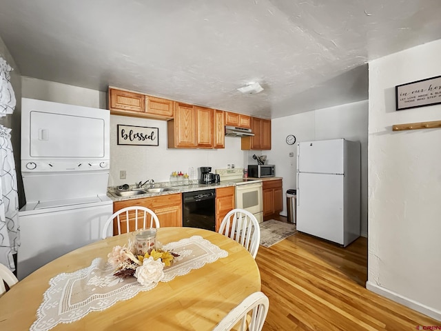 kitchen with white appliances, stacked washer and dryer, light hardwood / wood-style floors, and sink