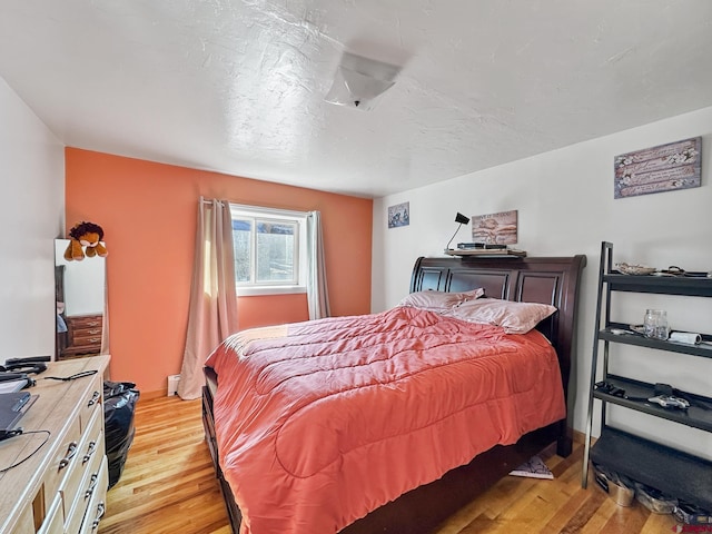 bedroom featuring light hardwood / wood-style flooring and a baseboard heating unit