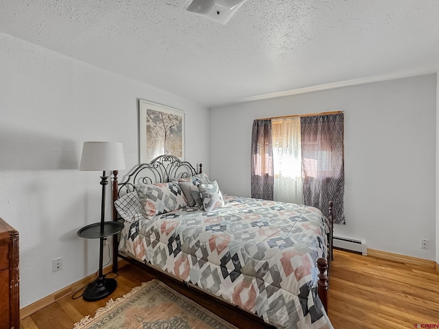 bedroom with hardwood / wood-style floors, a textured ceiling, and a baseboard radiator