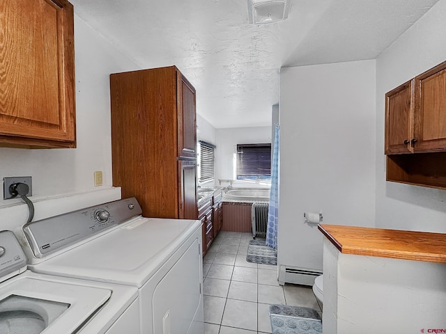 washroom featuring radiator heating unit, baseboard heating, washing machine and dryer, a textured ceiling, and light tile patterned flooring