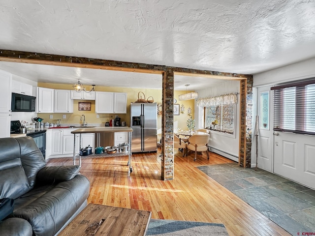 living room featuring light hardwood / wood-style flooring, a baseboard radiator, a textured ceiling, and sink