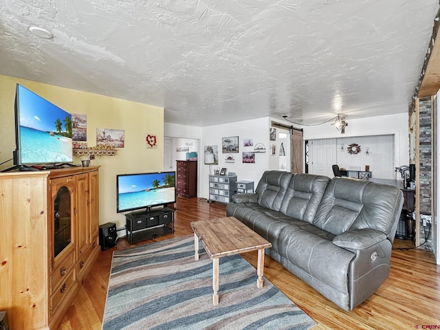 living room with a barn door, wood-type flooring, and a textured ceiling