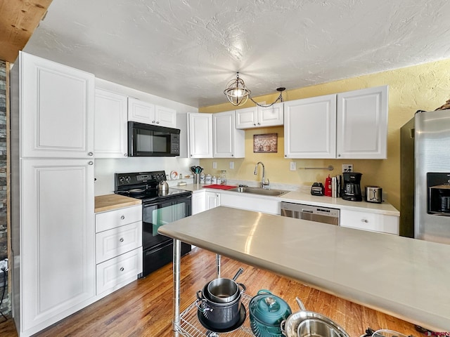 kitchen featuring sink, light hardwood / wood-style flooring, a textured ceiling, white cabinets, and black appliances