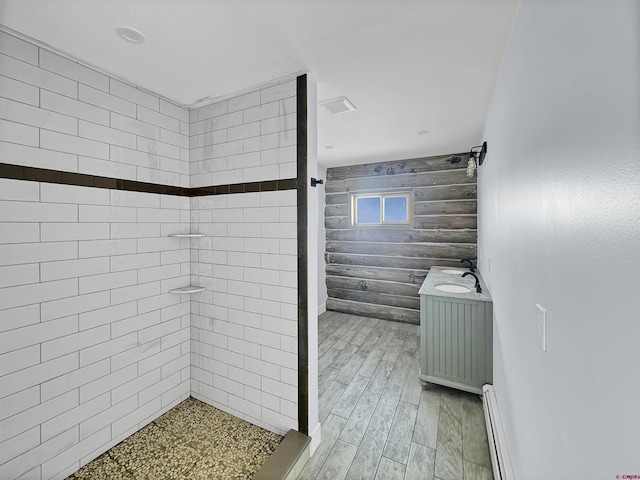 full bathroom featuring tiled shower, baseboard heating, and wood finished floors