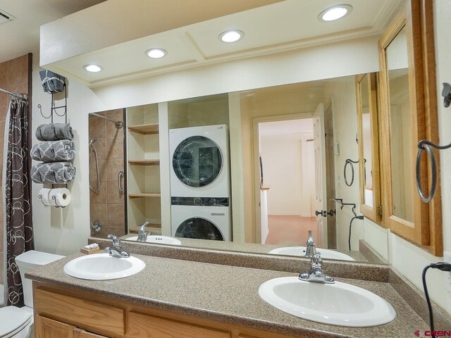 bathroom with curtained shower, vanity, stacked washer and clothes dryer, and toilet