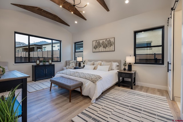 bedroom featuring lofted ceiling with beams, ceiling fan, a barn door, and light hardwood / wood-style flooring