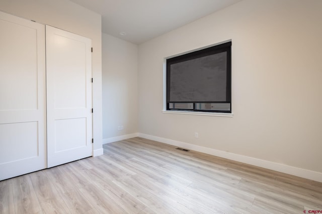 unfurnished bedroom featuring light hardwood / wood-style flooring and a closet