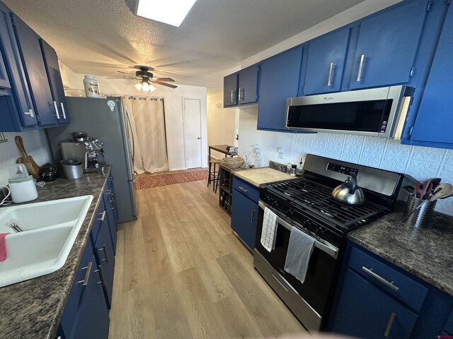 kitchen featuring sink, blue cabinets, stainless steel appliances, and light hardwood / wood-style flooring