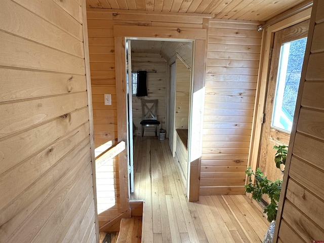 hallway featuring light hardwood / wood-style floors, wooden walls, and wood ceiling