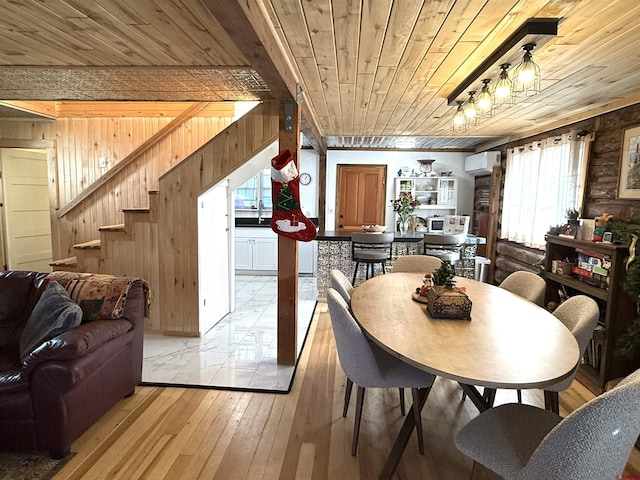 dining space featuring wood walls, light wood-type flooring, a wall mounted AC, and wooden ceiling