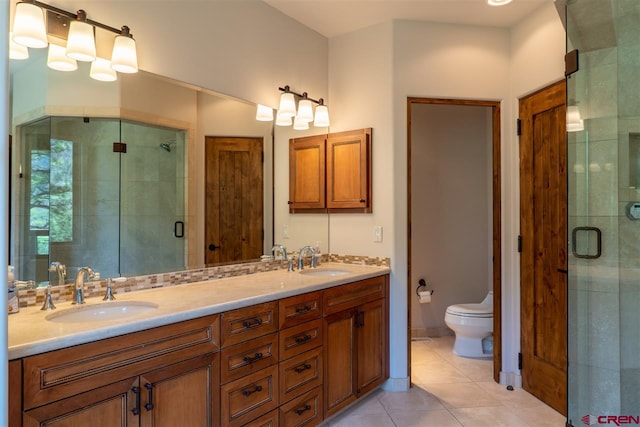 bathroom featuring tile patterned flooring, vanity, toilet, and a shower with door