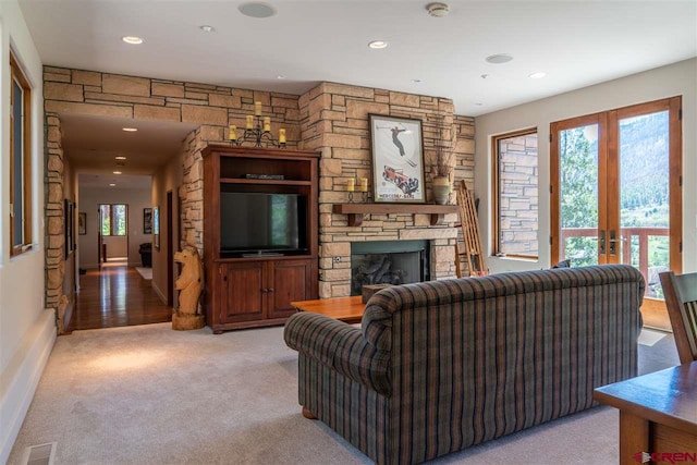 carpeted living room with a stone fireplace and french doors