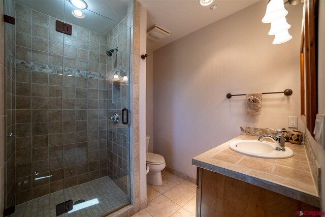 bathroom featuring tile patterned flooring, vanity, an enclosed shower, and toilet