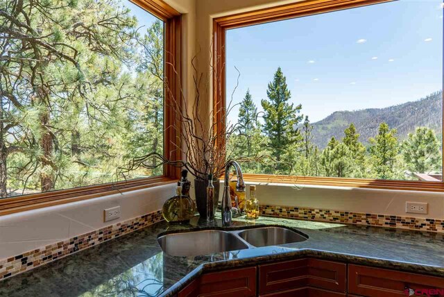 interior space featuring a mountain view, decorative backsplash, sink, and dark stone counters