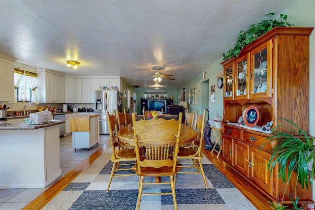 dining area with a textured ceiling, light hardwood / wood-style flooring, and ceiling fan