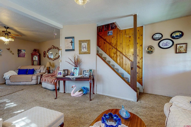 living room featuring carpet flooring, a textured ceiling, ceiling fan, and wooden walls