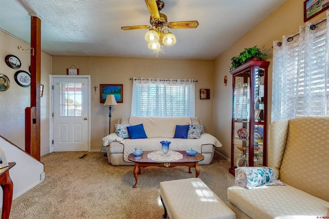 living room with a textured ceiling, light colored carpet, and ceiling fan