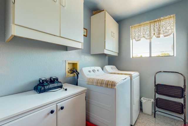 clothes washing area with cabinets, light tile patterned floors, and washer and dryer