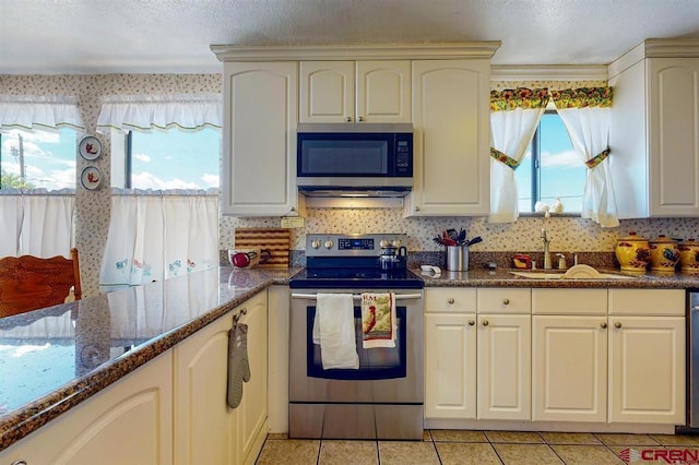 kitchen with sink, light tile patterned floors, a healthy amount of sunlight, and appliances with stainless steel finishes