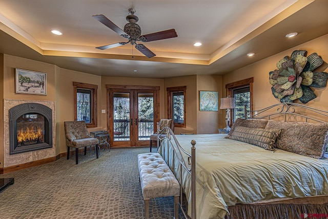 bedroom featuring multiple windows, access to outside, ceiling fan, and a tray ceiling