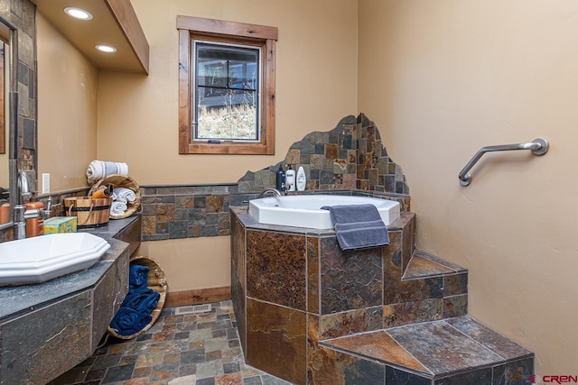 bathroom featuring vanity and a relaxing tiled tub