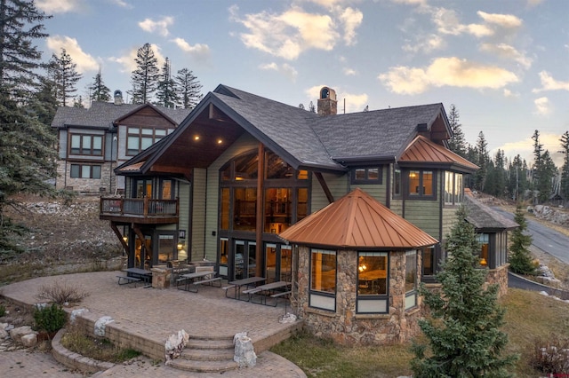 back house at dusk featuring a patio area