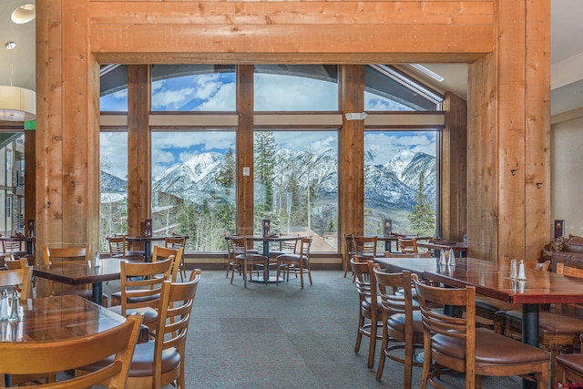 carpeted dining room with a mountain view and vaulted ceiling