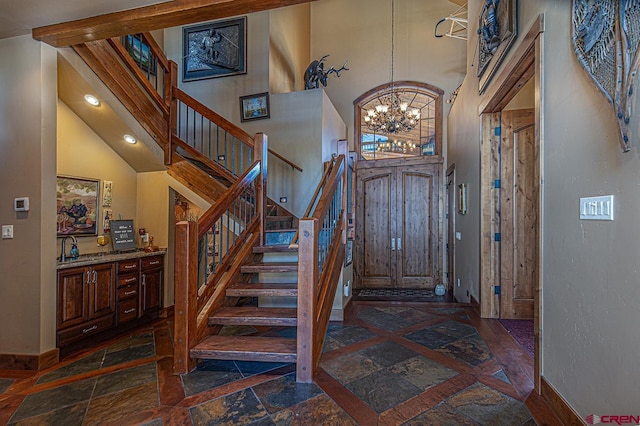 foyer entrance with a towering ceiling, a notable chandelier, and sink