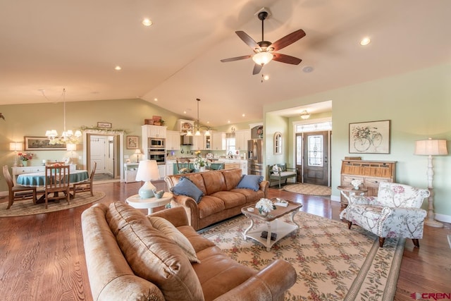 living room featuring vaulted ceiling, ceiling fan with notable chandelier, and hardwood / wood-style flooring