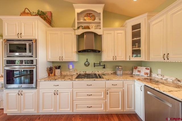 kitchen featuring white cabinetry, light stone countertops, wall chimney exhaust hood, stainless steel appliances, and lofted ceiling