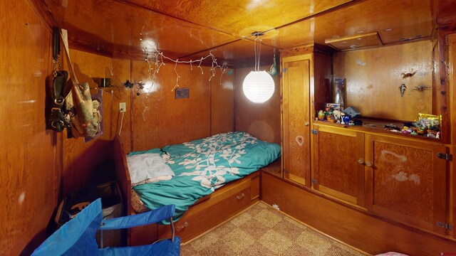 bedroom featuring light carpet and wooden walls