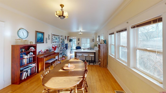 dining space with a healthy amount of sunlight, ornamental molding, and light hardwood / wood-style flooring